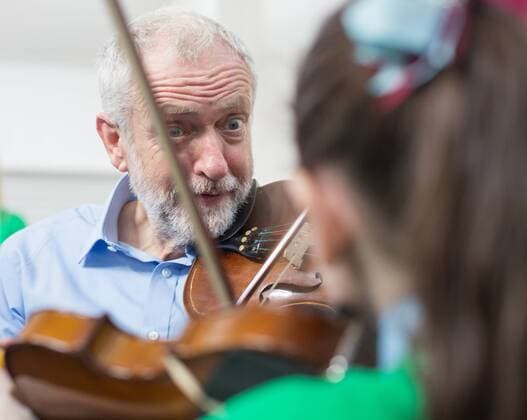 September 27, 2016 - Liverpool, Merseyside, UK - Liverpool , UK . Labour Party leader JEREMY CORBYN is shown how to play the violin by JESSICA KELLY (10) during a visit to Faith Primary School in Liverpool , where he listens to and then joins in with the school orchestra Liverpool UK  - ZUMAl94_