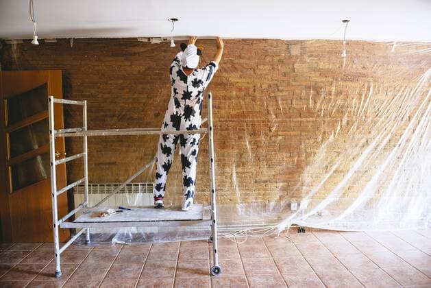 Woman disguised as a cow covering a wall with plastic before painting model released Symbolfoto property released  GEMF000957