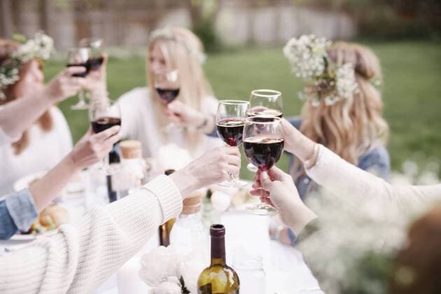 Group of female friends gathered around a table, toasting with red wine. Group of female friends gathered around a table, toasting with red wine.  22487