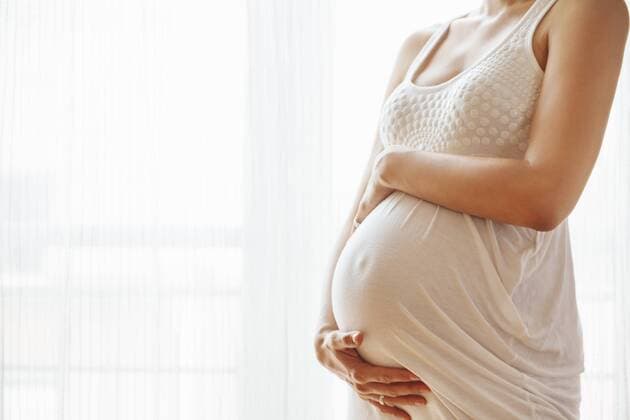 Pregnant woman holding her belly, copy space model released Symbolfoto  ZEDF000278