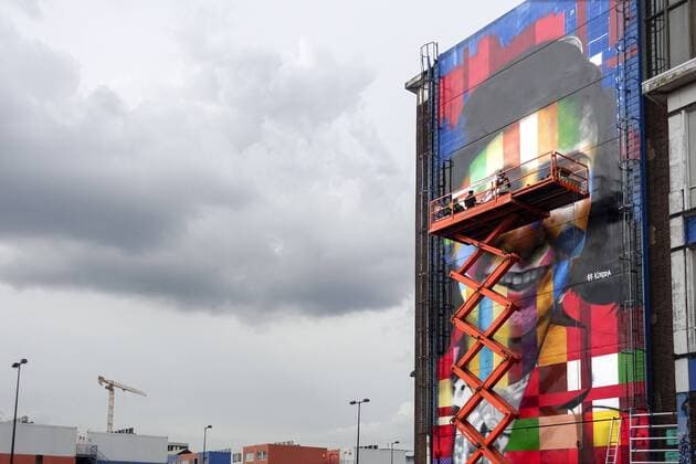 The Netherlands, Amsterdam. The famous Brazilian street artist Eduardo Kobra realizes this week a monumental portrait of Anne Frank. 26 september 2016, Photo: Katrien Mulder Hollandse Hoogte Nederland, Amsterdam, Amsterdam Noord, NDSM Terrein, wereldberoende Braziliaanse streetartist Eduardo Kobra realiseert deze week een monumentaal portret van Anne Frank op de zuidelijke buitenmuur van de loods op de hoek van de MS van Riemsdijkweg, en de Tt Neveritaweg, famous Brazilian street artist Eduardo Kobra realizes this week a monumental portrait of Anne Frank, de man rechts in de hoogwerker is Eduardo Kobra, the man at the right side of the platform is Eduardo Kobra, 26 september 2016, foto: Katrien Mulder  59396751