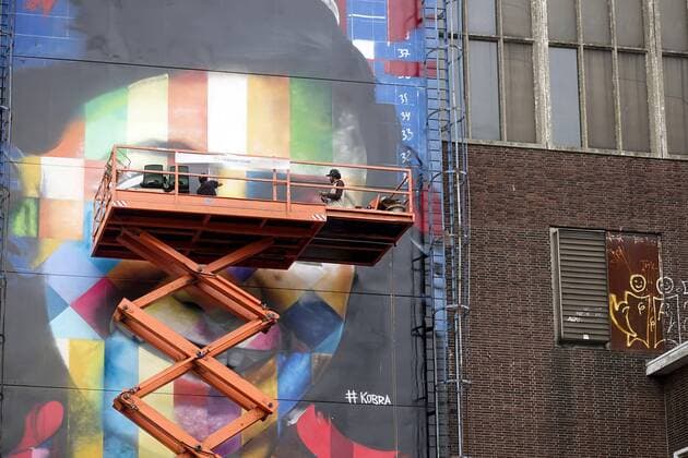 The Netherlands, Amsterdam. The famous Brazilian street artist Eduardo Kobra realizes this week a monumental portrait of Anne Frank. 26 september 2016, Photo: Katrien Mulder Hollandse Hoogte Nederland, Amsterdam, Amsterdam Noord, NDSM Terrein, wereldberoende Braziliaanse streetartist Eduardo Kobra realiseert deze week een monumentaal portret van Anne Frank op de zuidelijke buitenmuur van de loods op de hoek van de MS van Riemsdijkweg, en de Tt Neveritaweg, famous Brazilian street artist Eduardo Kobra realizes this week a monumental portrait of Anne Frank, de man rechts in de hoogwerker is Eduardo Kobra, the man at the right side of the platform is Eduardo Kobra, 26 september 2016, foto: Katrien Mulder  59396756