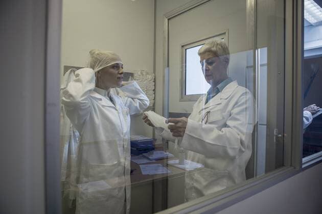 Two lab technicians putting on sterile protective clothing model released Symbolfoto property released  ZEF010018