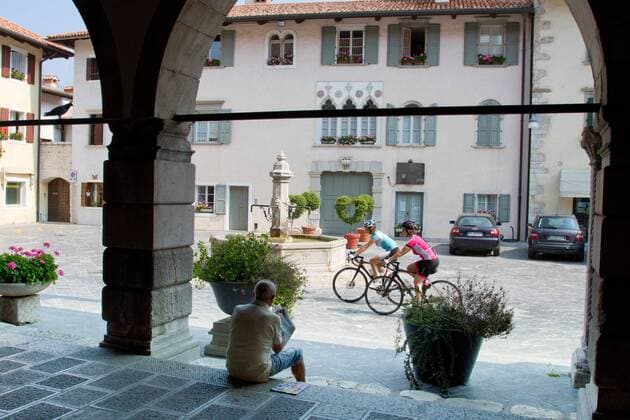 Rennradfahrer auf dem Alpe Adria-Weg auf der Piazza in Venzone, 1976 vom Erdbeben zerstört und wieder aufgebaut Venzone Nord-Italien Italien Alpe-Adria-Weg