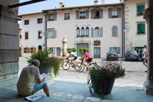 Rennradfahrer auf dem Alpe Adria-Weg auf der Piazza in Venzone, 1976 vom Erdbeben zerstört und wieder aufgebaut Venzone Nord-Italien Italien Alpe-Adria-Weg