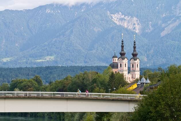 Rennradfahrer auf der Brücke vor der heiligen Kreuz Kirche in Villach Villach Kärnten Österreich