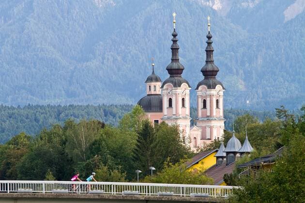 Rennradfahrer auf der Brücke vor der heiligen Kreuz Kirche in Villach Villach Kärnten Österreich