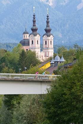 Rennradfahrer auf der Brücke vor der heiligen Kreuz Kirche in Villach Villach Kärnten Österreich