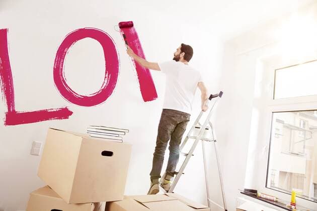 Young man painting the word LOVE on a wall in new apartment model released Symbolfoto property released  MFF003270