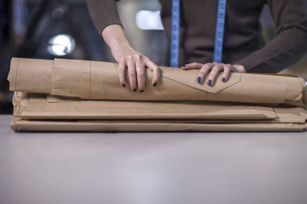 Fashion designer folding up sheet samples in clothing factory model released Symbolfoto property released  ZEF10523