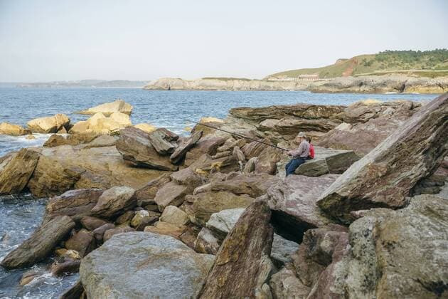 Grandfather and grandson fishing together at the sea sitting on rock model released Symbolfoto  DAPF00425