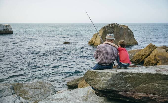 Grandfather and grandson fishing together at the sea sitting on rock model released Symbolfoto  DAPF00429