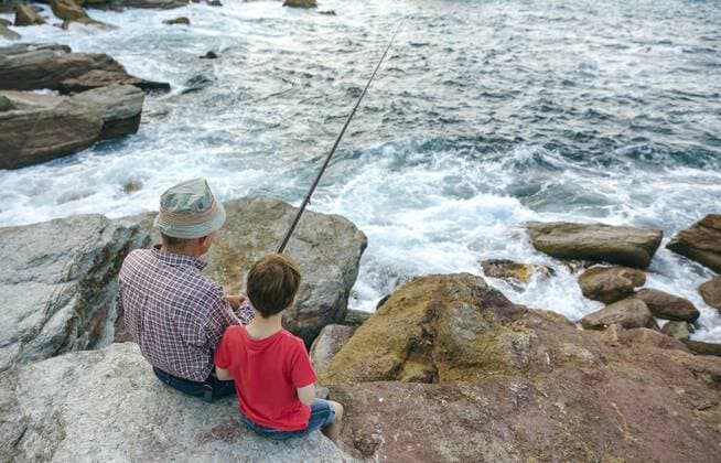 Grandfather and grandson fishing together at the sea sitting on rock model released Symbolfoto  DAPF00430
