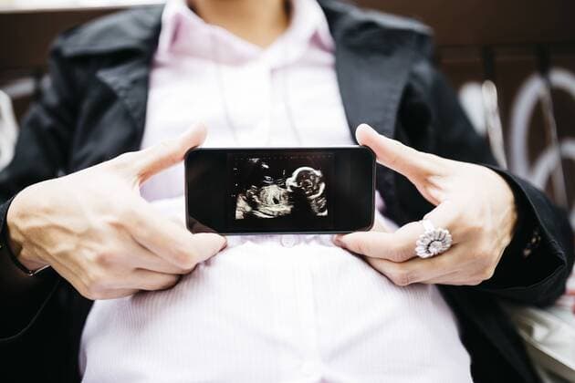 Pregnant woman showing ultrasound image on cell phone model released Symbolfoto property released  JRFF01009