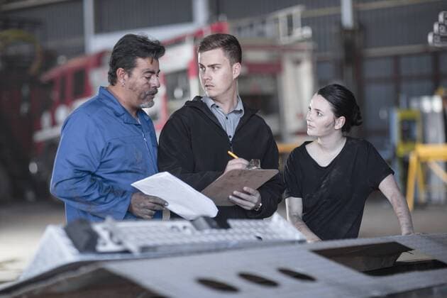 Mechanics working at fire brigade workshop reading check list model released Symbolfoto property released  ZEF11704
