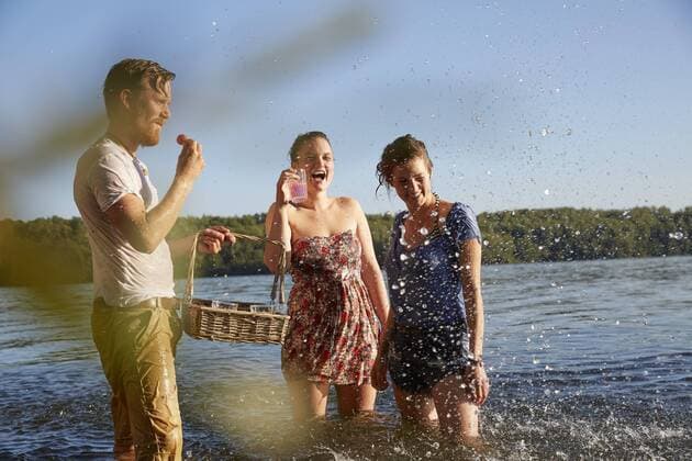 Playful friends splashing in a lake taking a drink model released Symbolfoto  FMKF03282