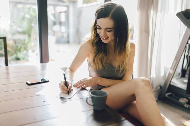 Smiling young woman writing at home model released Symbolfoto property released  GIOF01627