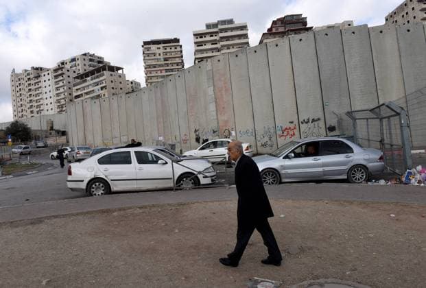 A Palestinian walks near the Israeli separation wall that surrounds the Shurafat Refugee Camp northeast of Jerusalem, January 15, 2017. Representatives of 72 countries are meeting today in Paris for a one day Peace Summit in the latest bid to restart peace talks between Israel and the Palestinians. Israeli Prime Minister Benjamin Netanyahu says the Paris peace talks are useless while the Palestinians welcome the multinational approach to brings the two sides to the negotiating table.  JER2017011520 DEBBIExHILL