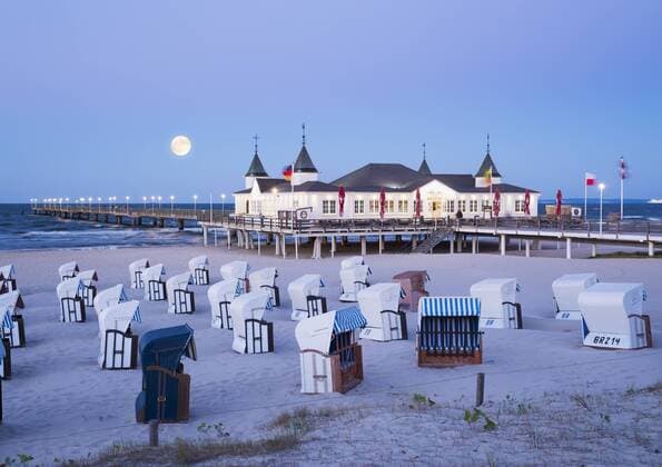 Germany, Usedom, Ahlbeck, view to sea bridge with hooded beach chairs in the foreground at dusk  SIEF07237