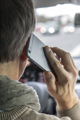 Mann, Autofahrer, benutzt ein Handy, während der Fahrt, ohne Freisprecheinrichtung,