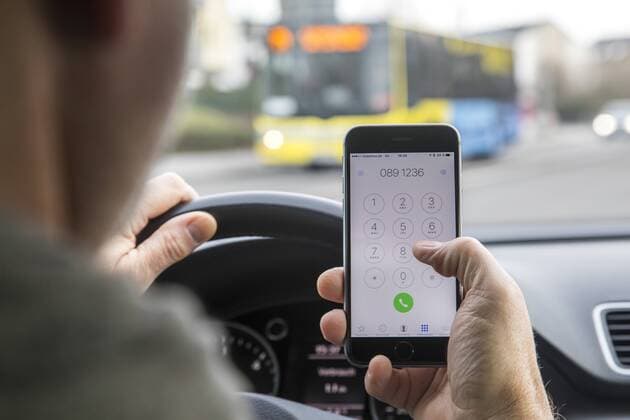 Mann, Autofahrer, benutzt ein Handy, während der Fahrt, wählt Telefonnummer, ohne Freisprecheinrichtung,