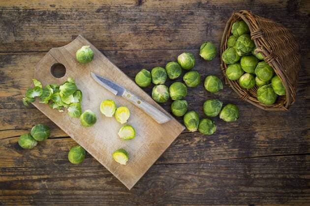 Brussels sprouts, kitchen knife and wooden board on dark wood  LVF05840