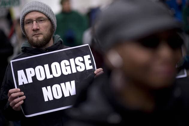 Gedenkmarsch Kolonialgeschichte DEU, Deutschland, Germany, Berlin, 25.02.2017 Demonstranten mit Plakat Apologise now, Entschuldigung sofort, beim 11. Gedenkmarsch zur Erinnerung an die afrikanischen Opfer von Versklavung, Kolonialismus und rassistischer Gewalt vom Komitee fuer ein afrikanisches Denkmal in Berlin und afrikanischer Vereine in Berlin. Dieser Gedenkmarsch wurde ins Leben gerufen, um der Forderung nach Anerkennung der Verbrechen gegen Schwarze Menschen und Menschen afrikanischer Herkunft Nachdruck zu verleihen. Anlass ist die Berliner Afrika-Konferenz von 1884 - 1885, auf der Afrika vor 130 Jahren unter den europaeischen Kolonialmaechten aufgeteilt wurde. Mehr als 30 Millionen Afrikanerinnen und Afrikaner wurden Opfer von Versklavung und kolonialen Verbrechen gegen die Menschlichkeit. Die von Deutschland an den Herero und Nama begangenen Voelkermorde in Namibia und die Kriegs