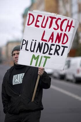 Gedenkmarsch Kolonialgeschichte DEU, Deutschland, Germany, Berlin, 25.02.2017 Demonstranten mit Plakat Deutschland pluendert Mit beim 11. Gedenkmarsch zur Erinnerung an die afrikanischen Opfer von Versklavung, Kolonialismus und rassistischer Gewalt vom Komitee fuer ein afrikanisches Denkmal in Berlin und afrikanischer Vereine in Berlin. Dieser Gedenkmarsch wurde ins Leben gerufen, um der Forderung nach Anerkennung der Verbrechen gegen Schwarze Menschen und Menschen afrikanischer Herkunft Nachdruck zu verleihen. Anlass ist die Berliner Afrika-Konferenz von 1884 - 1885, auf der Afrika vor 130 Jahren unter den europaeischen Kolonialmaechten aufgeteilt wurde. Mehr als 30 Millionen Afrikanerinnen und Afrikaner wurden Opfer von Versklavung und kolonialen Verbrechen gegen die Menschlichkeit. Die von Deutschland an den Herero und Nama begangenen Voelkermorde in Namibia und die Kriegsverbrechen i