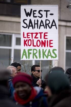Gedenkmarsch Kolonialgeschichte DEU, Deutschland, Germany, Berlin, 25.02.2017 Demonstranten mit Plakat Referendum Jetzt West-Sahara letzte Kolonie in Afrika gegen die Besetzung der Sahara durch Marokko und Deutschland pluendert Mit beim 11. Gedenkmarsch zur Erinnerung an die afrikanischen Opfer von Versklavung, Kolonialismus und rassistischer Gewalt vom Komitee fuer ein afrikanisches Denkmal in Berlin und afrikanischer Vereine in Berlin. Dieser Gedenkmarsch wurde ins Leben gerufen, um der Forderung nach Anerkennung der Verbrechen gegen Schwarze Menschen und Menschen afrikanischer Herkunft Nachdruck zu verleihen. Anlass ist die Berliner Afrika-Konferenz von 1884 - 1885, auf der Afrika vor 130 Jahren unter den europaeischen Kolonialmaechten aufgeteilt wurde. Mehr als 30 Millionen Afrikanerinnen und Afrikaner wurden Opfer von Versklavung und kolonialen Verbrechen gegen die Menschlichkeit. D
