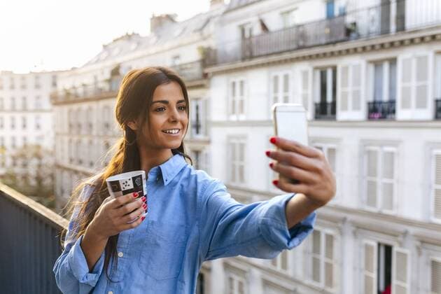 Young woman standing on balcony takinf smart phone selfie model released Symbolfoto  MGOF02869