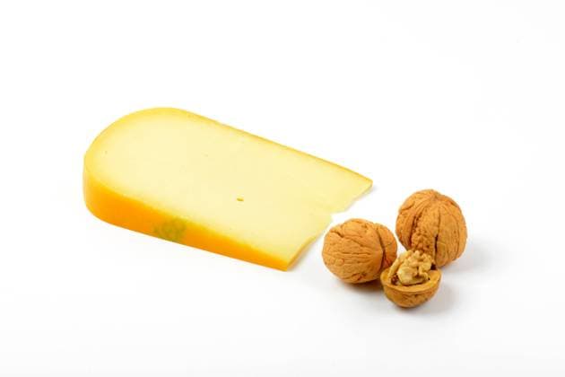 slice of gouda cheese with walnuts on white background CTKPhotoF201703101042301 