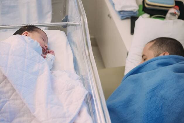 Father sleeping next to his newborn baby girl in hospital model released Symbolfoto  GEMF01531