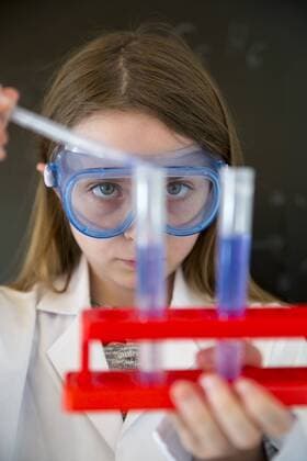 IMAGO Creative: NGO, Ausbildung für Kinder Portrait of girl wearing work coat and safety glasses doing chemical experiment model released Symbolfoto  SARF03227