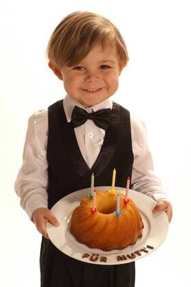 Ein kleiner Junge im Anzug mit einem selbstgebackenen Kuchen fuer die Mutti, Model-Release, 2006