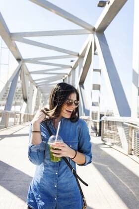 Spain, Barcelona, laughing young woman with beverage on a bridge model released Symbolfoto  VABF01274