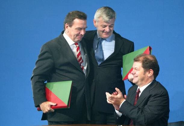 Unterschrift unter die Koalitionsvereinbarung zwischen SPD und Gruene : Bundeskanzler Gerhard Schroeder (l), SPD, und Bundesaussenminister Joschka Fischer, Gruene, umarmen sich. Es applaudiert Olaf Scholz, designierter SPD Generalsekretaer. Berlin, 16.10.2002, Berlin Deutschland Copyright: xThomasxKoehlerx