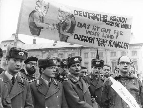 Mehr als 3000 Dresdener bereiteten Bundeskanzler Helmut Kohl vor dem Bellevue Hotel einen begeisterten Empfang. Hier zu sehen ein Transparent mit der Aufschrift Deutsche reichen sich die Hand, das ist gut fuer unser Land. Desden gruesst den Kanzler , im Vordergrund DDR Volkspolizisten und ein Mitgled des neuen Forums . Dresden den 19.12.1990, Â Dresden Deutschland Copyright: xThomasxImox