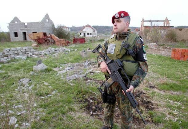 Ein deutscher Soldat der KFOR haelt Wache in einem Dorf serbischer Heimkehrer . Der Wiederaufbau des Dorfes ist Teil eines sogenannten CIMIC - Projektes . Die KFOR leistet Hilfe bei Infrastruktur-Massnahmen und schuetzt die Bewohner vor moeglichen Uebergriffen aus der Bevoelkerung . Nowake , Kosovo , 16.04.2003 , Nowake Kosovo Copyright: xT.xKxoxexhxlxexrx