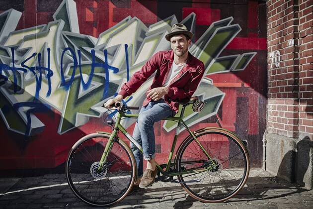 Germany, Hamburg, St. Pauli, Man sitting on bicycle in front of graffiti model released Symbolfoto  RORF00832