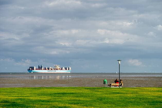 zwei Personen sitzen auf einer Bank an der Kueste und schauen zum Containerschiff der Maersk Line im Jadebusen, Deutschland, Niedersachsen, Schillig two persons sitting on a bench and looking at the container ship of Maersk Line in the Jade Bight, Germany, Lower Saxony, Schillig BLWS455507 Copyright: xblickwinkel McPHOTO W.xBoyungsx