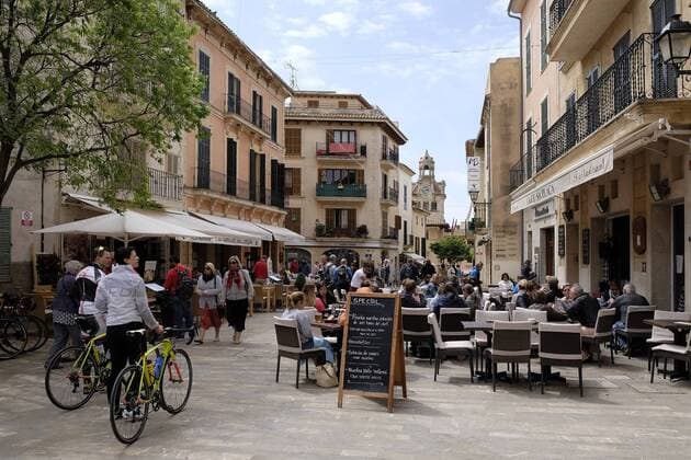 Spanien, Baleraren, Mallorca, Alcudia, Die Stadt Alcudia ist die aelteste Stadt Mallorcas (Gruendung 123 v. Chr. als roemische Siedlung Pollencia) im Norden der Insel. Alcudia hat aus jeder Richtung kommend mittelalterliche Stadttore. Die Stadtmauern sind rundum die Stadt erhalten und wurden restauriert. Aber nur auf der Nordwestseite sind sie gesichert und auf einer Laenge von etwa 500 Metern begehbar. Blick in den Fussgaengerbereich im Zentrum mit zahlreichen Cafes und Restaurants. Ferieninsel Mallorca