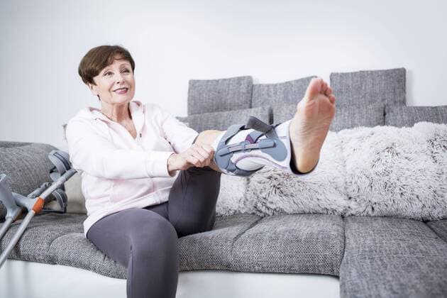Senior woman putting on splint for her leg model released Symbolfoto property released  WESTF23284