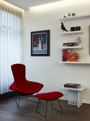 Designklassiker von Ray und Charles Eames Red armchair and footstool with book shelving in Compass Court Apartment, Shad Thames, London, England, UK United Kingdom  Copyright: xDavidxChurchillx 15009-50-1