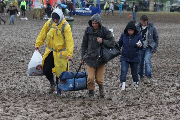 TVER REGION, RUSSIA â€“ JULY 9, 2017: Festival-goers wearing raincoats and rubber boots walk through mud at the 2017 Nashestvie open air rock music festival. Alexander Ryumin TASS  TS056ADD