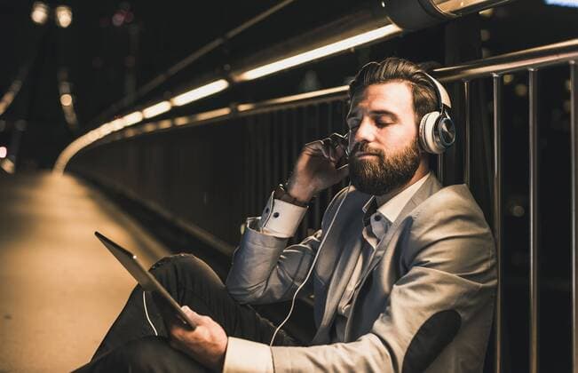Young man with tablet and headphones sitting on bridge at night model released Symbolfoto  UUF10909