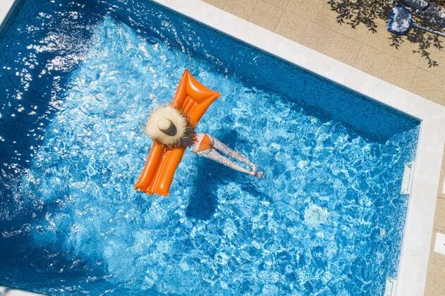 Back view of woman relaxing on orange airbed in swimming pool model released Symbolfoto property released  MAEF12347