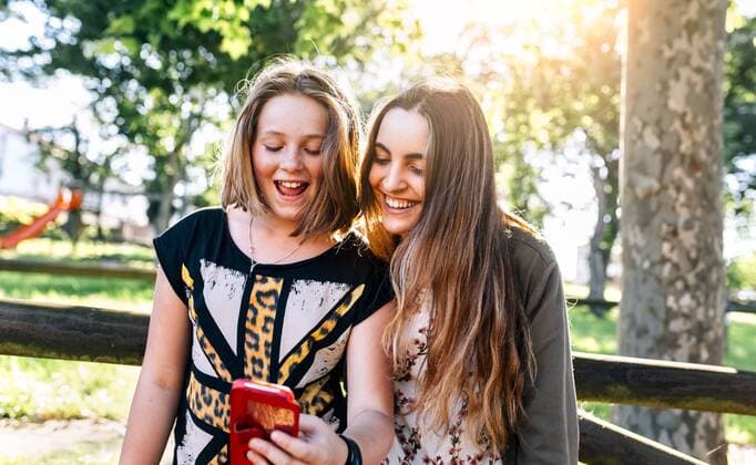 Two girls having fun with their smartphone outdoors model released Symbolfoto  MGOF03449