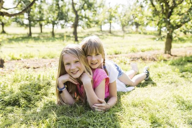 Two smiling sisters lying on meadow model released Symbolfoto property released  SHKF00775