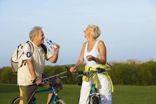Senior couple riding their bikes on a beautiful day in autumn and drinking water  A5