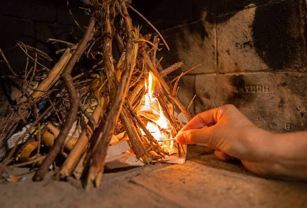 24.08.2017, Nybro, Schweden, SWE - Ein Holzscheit im Kamin wird angezündet. (Kamin, offener Kamin, Feuer, Feuerstelle, offen, Ofen, Holzfeuer, Holz, Brennholz, offener, Festbrennstoff, Festbrennstoffe, nachwachsender Rohstoff, Rohstoff, Wärme, Heizung, heizen, Kaminfeuer, Holzscheit, Brennstoff, Holzverbrennung, CO2-neutral, CO2, Neutral, CO2 Neutral, Papir, anzünden, Anzünder, Streichholz, Hand, Finger, entfachen, Zeitung, Zeitungspapier, Stock, Stöcker). .